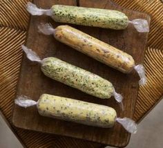 four pickles wrapped in plastic sitting on a cutting board