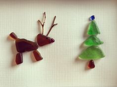 two glass reindeer ornaments are hanging on a white wall next to a small christmas tree