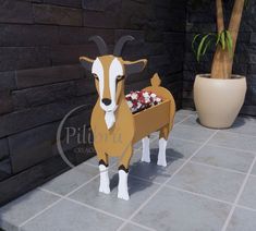 a cardboard goat standing next to a potted plant