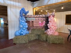 some hay bales and balloons in the shape of animals on display at a party