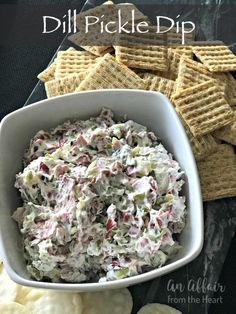 a bowl full of dip next to crackers and chips on a table with the words, dill pickle dip