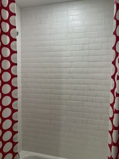 a white bath tub sitting next to a red and white shower curtain