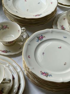 a table topped with lots of white and gold plates covered in floral design on top of each other