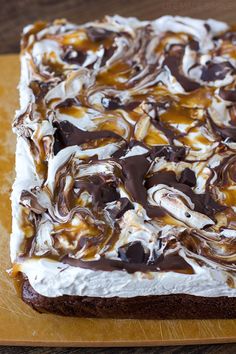 a square cake with chocolate and marshmallows on it sitting on a cutting board