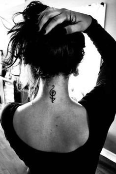 the back of a woman's neck with an anchor tattoo on her left side