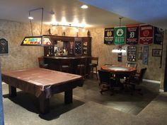 a game room with a pool table, bar and several other items on display in it