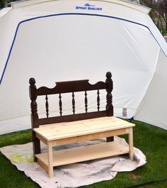 a wooden bench sitting on top of a lush green field next to a white tent