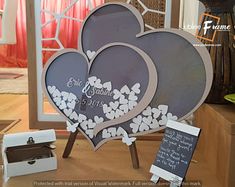 two heart shaped signs sitting on top of a wooden table next to a box and flowers