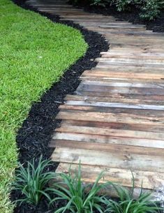 a wooden walkway in the middle of some grass