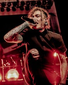 a man with tattoos on his arm singing into a microphone