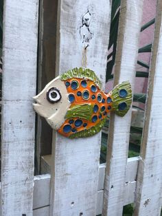 a ceramic fish hanging on the side of a white fence