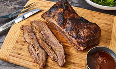 sliced steak on cutting board with sauce and salad