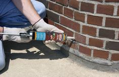 a person painting a brick wall with paint rollers and a spray bottle on the ground