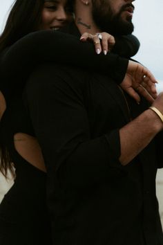 a man and woman hugging each other on the beach