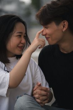 a man and woman sitting next to each other on top of a cement bench together