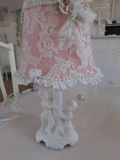 a white lamp with pink and white lace on it