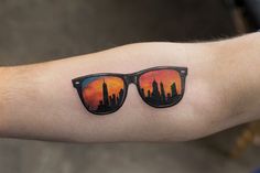 a man's arm with a pair of sunglasses on it and the skyline reflected in them