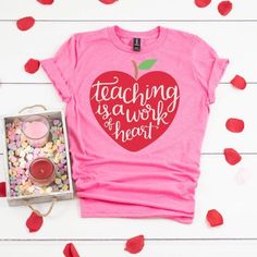 a pink shirt with the words teaching is a work of heart on it, surrounded by confetti