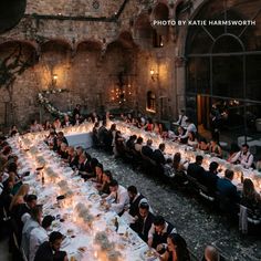 a large group of people sitting at long tables with candles in front of them on the floor