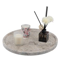 a marble table with two candles and some flowers on the top, next to a candle holder