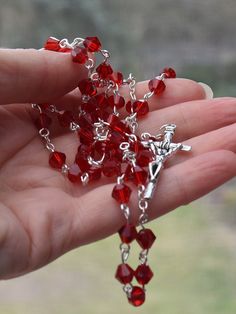 A beautiful five decade Rosary handmade with red cristal glass beads. Rosary circuit - 27,5 inches (70cm), which makes this perfect to pray with as well as wear around your neck. Features The crucifix measures 1.5 in (4cm) by0.8in (2cm). Beautiful, natural 6mm red glass beads Our Lady Medal Rosary Center Packaged in an organza gift bag. Handmade with love Average delivery times: Europe: 7 days USA: 10 days Handmade Red Rosary For Jewelry Making, Red Spiritual Rosary As Gift, Faceted Beads Crucifix Rosary As Gift, Handmade Red Rosary With Cross, Red Crucifix Rosary As Gift, Handmade Red Cross Rosary, Handmade Red Rosary, Handmade Red Crucifix Jewelry, Spiritual Red Crucifix Rosary