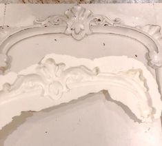 an ornate white piece of furniture is shown in close up view on the floor and wall