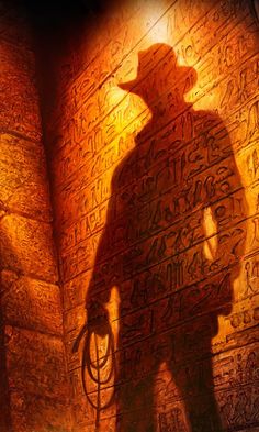 the shadow of a man standing in front of an egyptian wall with writing on it