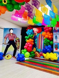 colorful balloons and streamers hang from the ceiling in front of a party room backdrop