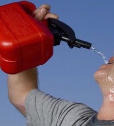 a man is spraying water on his face with a red container in front of him