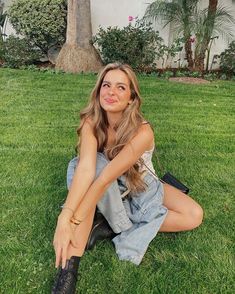 a woman sitting on the grass with her legs crossed