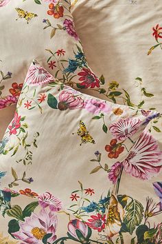 two pillows with colorful flowers on them sitting next to each other in front of a pillow case