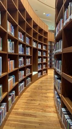 rows of books in a library with wooden shelves and hard wood flooring on both sides