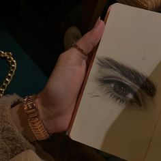 a person holding an open book in their left hand and looking at the viewer's eye