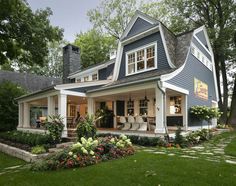 a house with blue siding and white trim on the front porch, covered in flowers