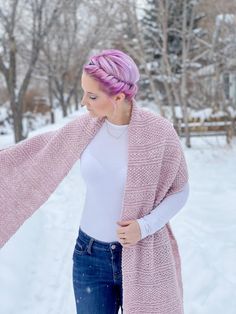 a woman standing in the snow wearing a pink cardigan