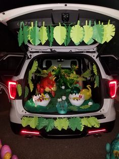 the trunk of a car is decorated with dinosaurs and plants