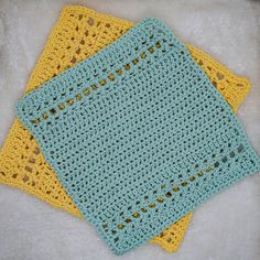 two crocheted yellow and blue squares on top of a white furnishing