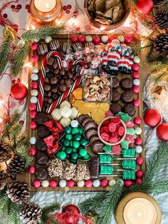 a tray filled with lots of candy and candies on top of a table next to candles