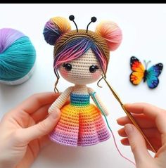 a crocheted doll is being held by someone's hands with yarn and scissors