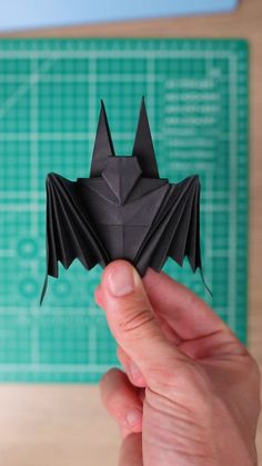 a hand holding up a black origami bat