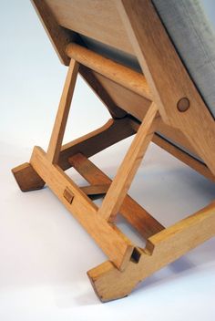 a wooden chair sitting on top of a white floor next to a gray seat cushion