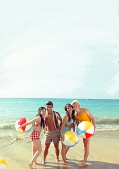 four people are standing on the beach with balls