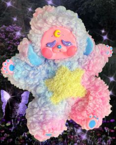 a colorful stuffed animal hanging from a string with stars on it's chest and wings