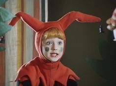 a young boy dressed up as a red rabbit with his nose painted white and ears curled back