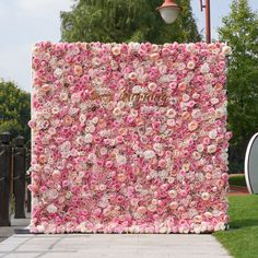 a large pink flowered wall in the middle of a sidewalk next to a lamp post