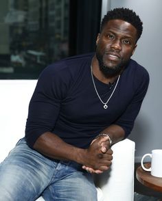 a man sitting on top of a white couch next to a cup