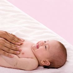 a baby laying on it's side being held up by a person with their hand