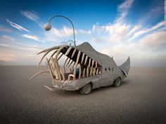 a car that is sitting in the sand with a skeleton on it's side