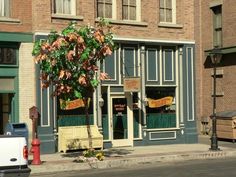 a storefront with a tree in front of it on the side of a street