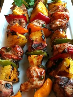 several skewers of meat and vegetables on a white plate